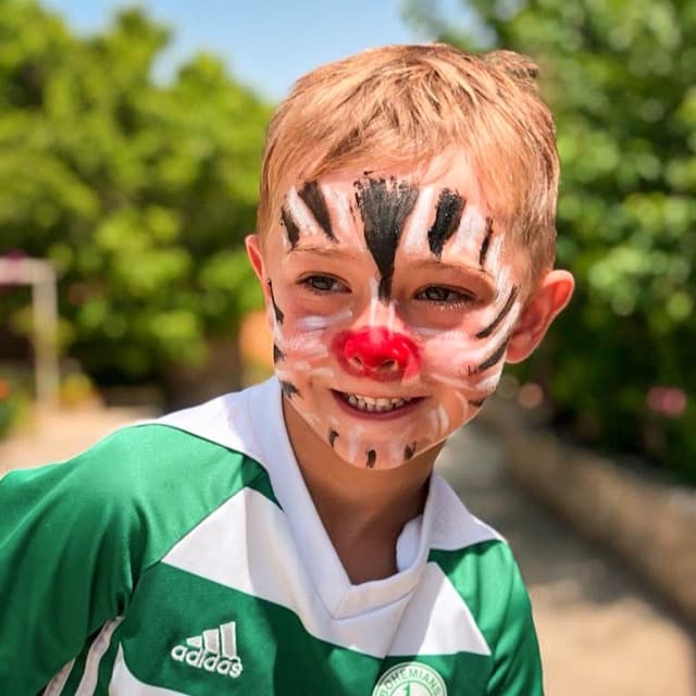 Boy in a green football jersey with tiger face paint